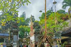 Arched bamboo penjor towers over altar piled high with prayer offerings for Kuningan Day
