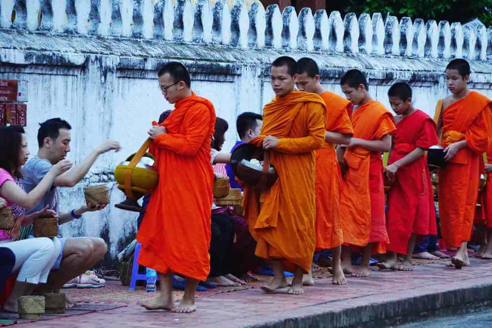 Buddhist monks receive donations of sticky rice during the daily alms-giving ritual in Luang Prabang, Laos