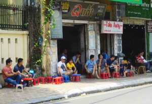 Diners sit on tiny plastic stools at a Vietnamese sidewalk cafe