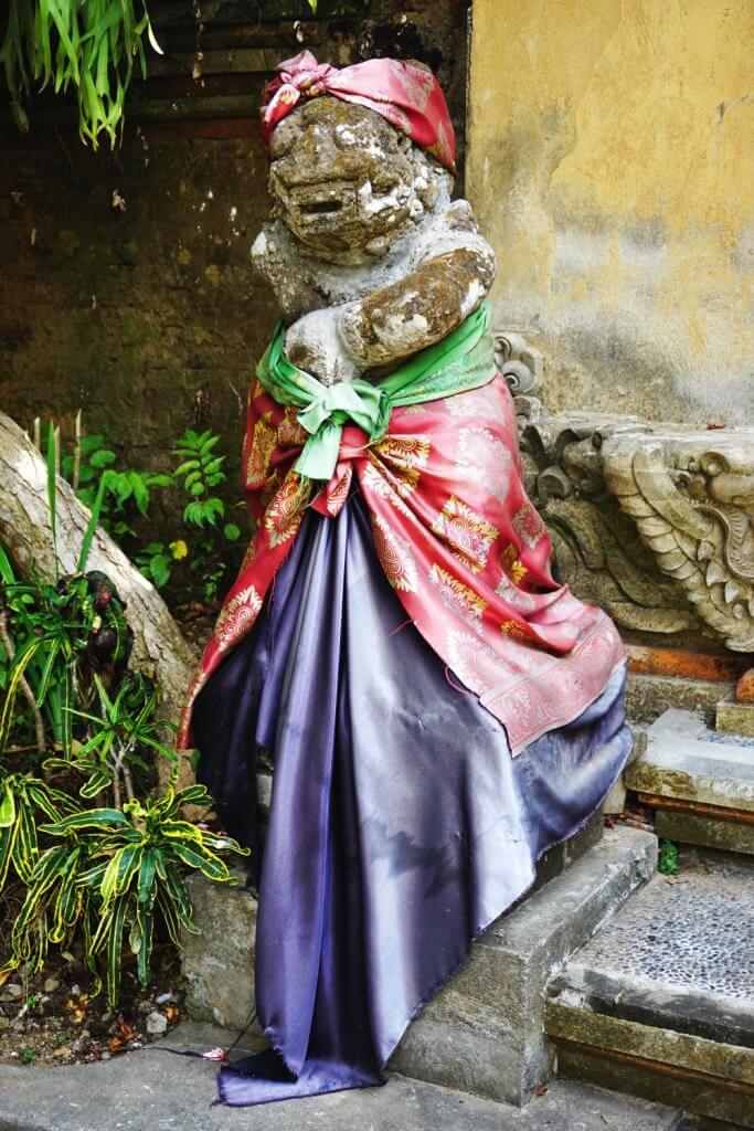 Stone Balinese temple figure with colorful sarongs and sash
