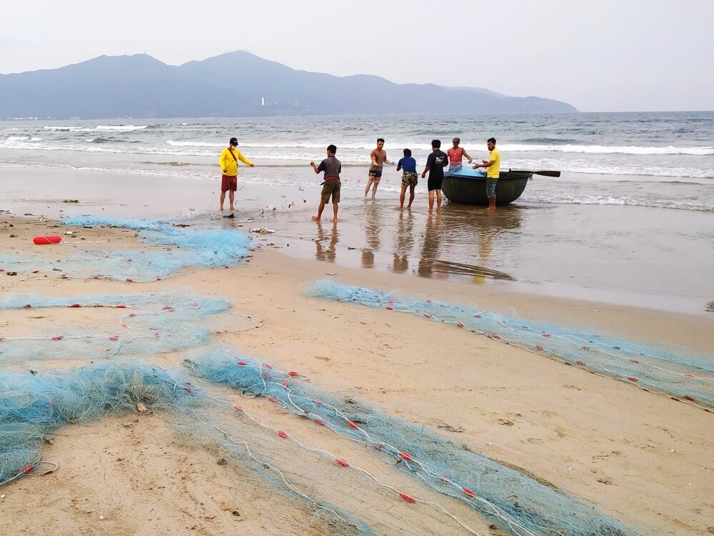 Vietnamese fishermen with nets on the beach in Danang