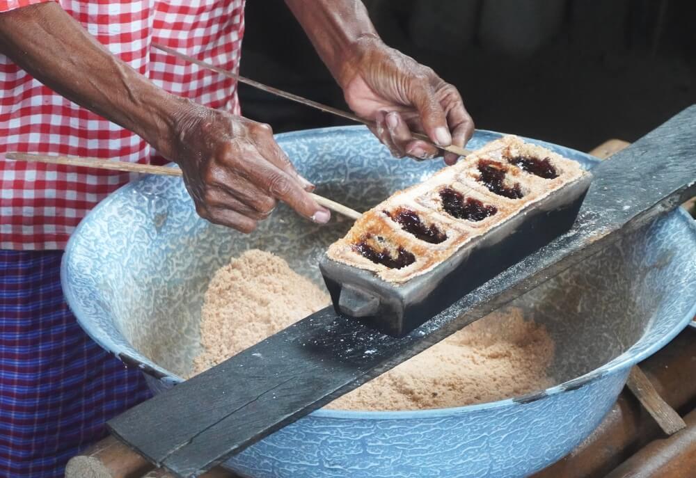 The roasted sago pockets, filled with shiny melted palm sugar are pried from the hot mold