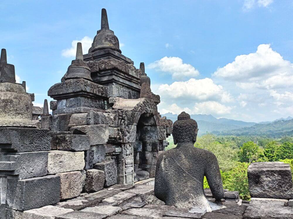 A stone Buddha gazes off to distant mountains from atop the Borobudur temple complex near Yogyakarta, Indonesia